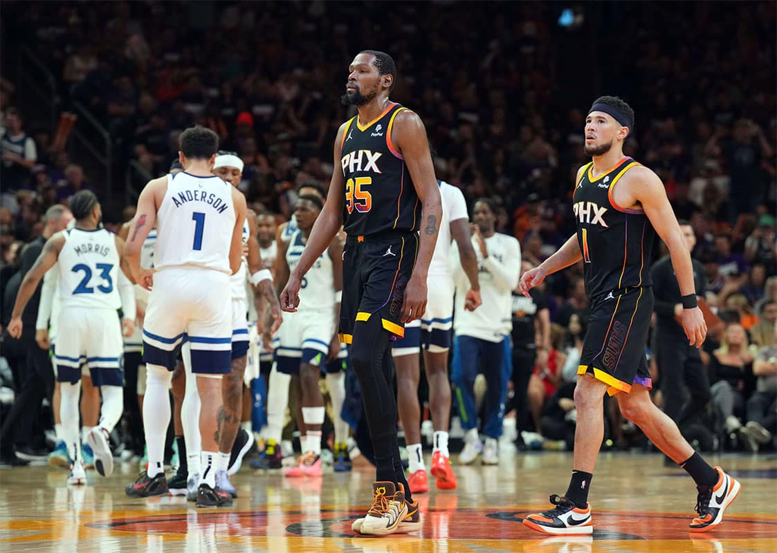 Phoenix Suns forward Kevin Durant (35) and Phoenix Suns guard Devin Booker (1) react while Minnesota Timberwolves players celebrate during the second half of game three of the first round for the 2024 NBA playoffs at Footprint Center.