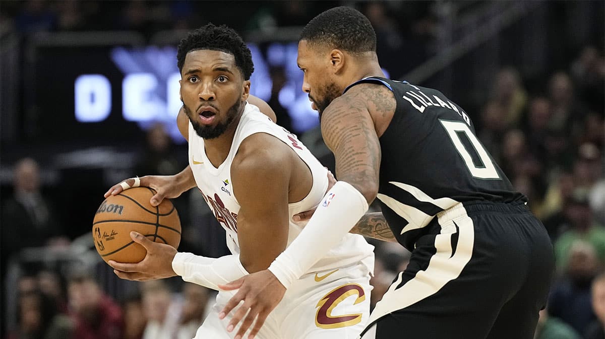 Cleveland Cavaliers guard Donovan Mitchell (45) holds the ball away from Milwaukee Bucks guard Damian Lillard (0) during the fourth quarter at Fiserv Forum.