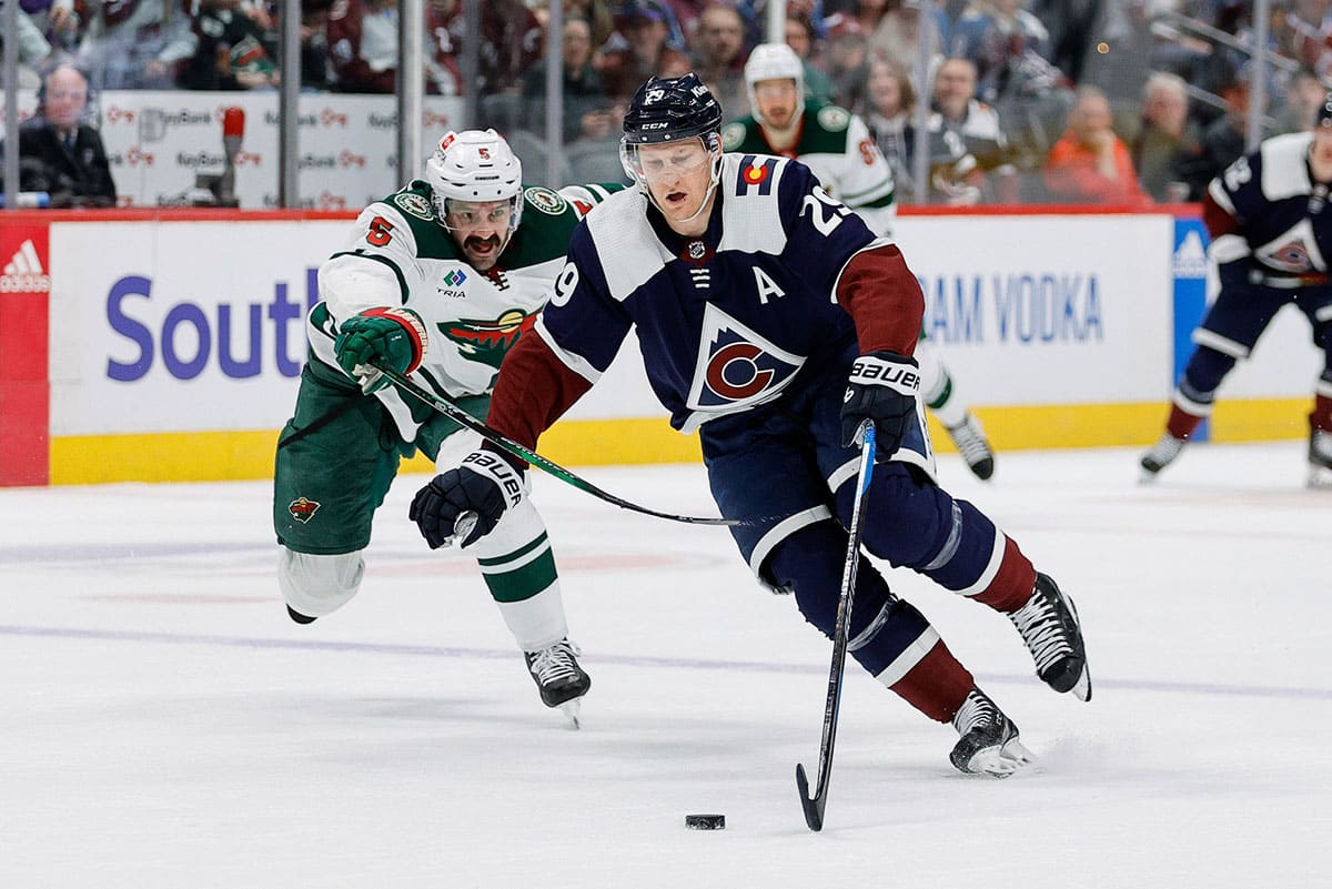 Colorado Avalanche center Nathan MacKinnon (29) controls the puck ahead of Minnesota Wild defenseman Jake Middleton (5) in the second period at Ball Arena