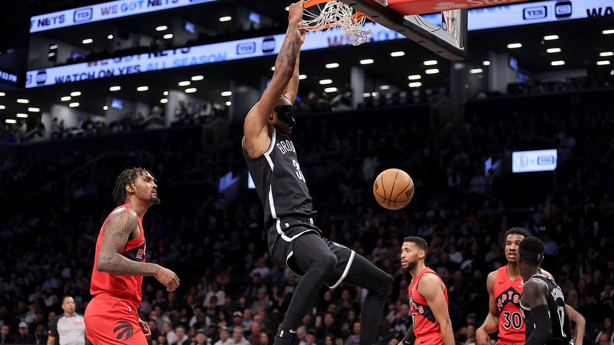 Brooklyn Nets center Nic Claxton (33) hangs on the rim after a dunk against Toronto Raptors center Malik Williams (35) and forward Garrett Temple (17) and guard Ochai Agbaji (30) during the first quarter at Barclays Center