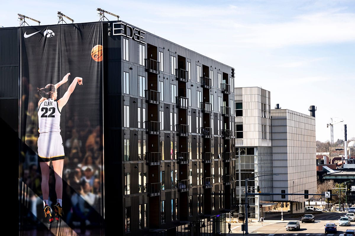 A Nike advertisement featuring Caitlin Clark making a 3-point basket is shown on a building in downtown Iowa City.