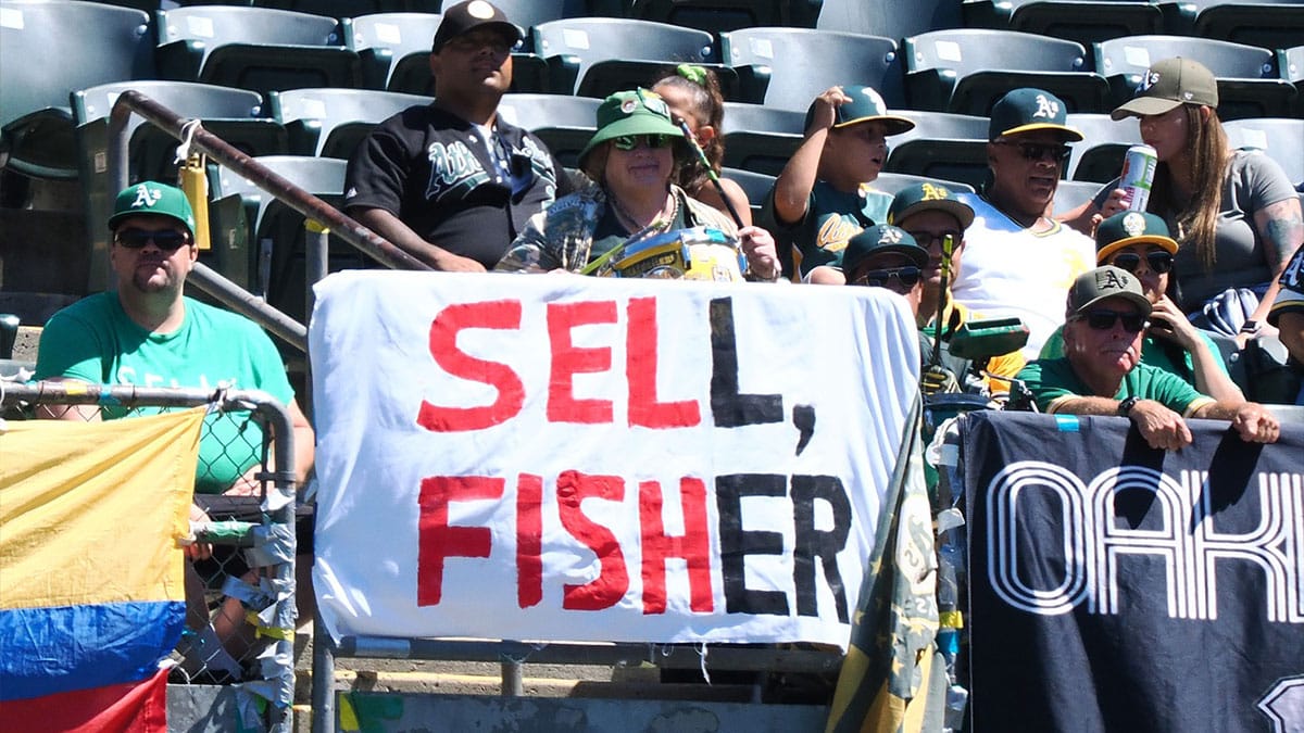 Oakland Athletics fans with a sign pleading for John Fisher to sell the MLB team