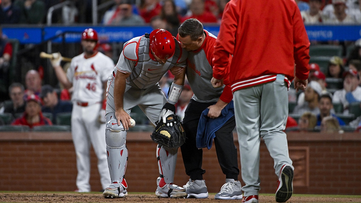 Philadelphia Phillies catcher J.T. Realmuto (10) is checked on by a trainer after he was hit in the throat by a wild pitch during the seventh inning against the St. Louis Cardinals at Busch Stadium.