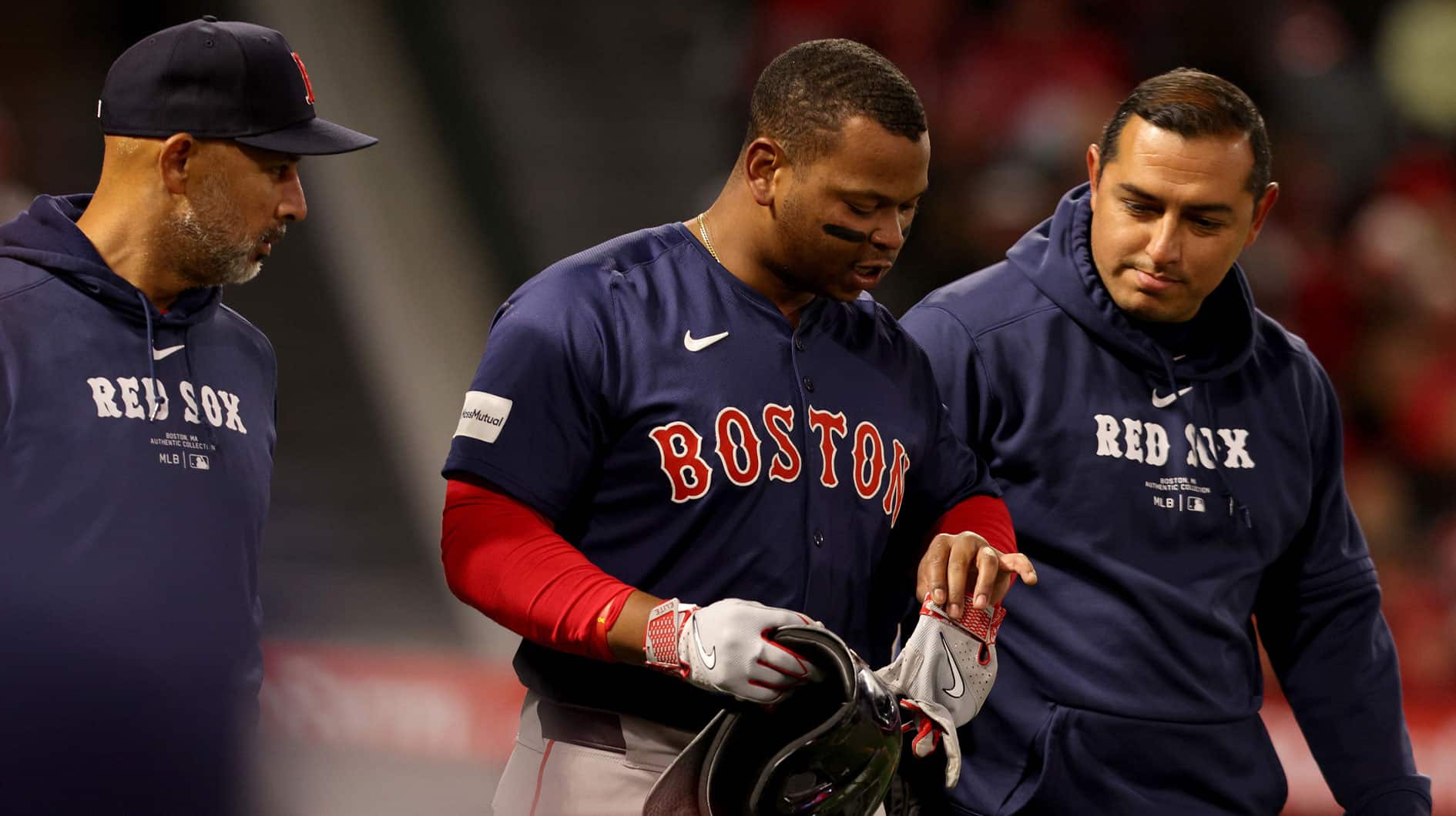 Boston Red Sox third baseman Rafael Devers (11) is checked by manager Alex Cora (left) and a trainer after being hit by a pitch during the sixth inning against the Los Angeles Angels at Angel Stadium.
