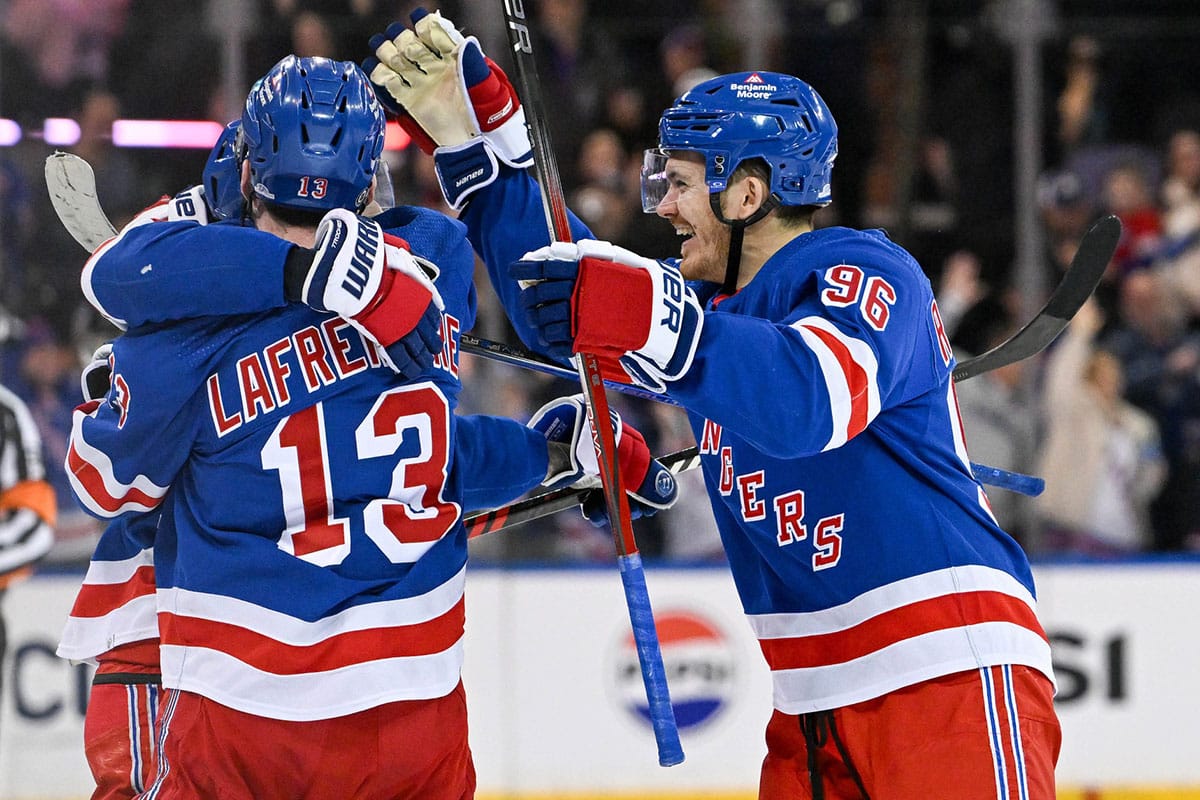 New York Rangers left wing Alexis Lafrenière (13) and New York Rangers center Jack Roslovic (96) celebrate with New York Rangers center Vincent Trocheck (16) after scoring the game clinching goal against the New York Islanders after shoot outs at Madison Square Garden.