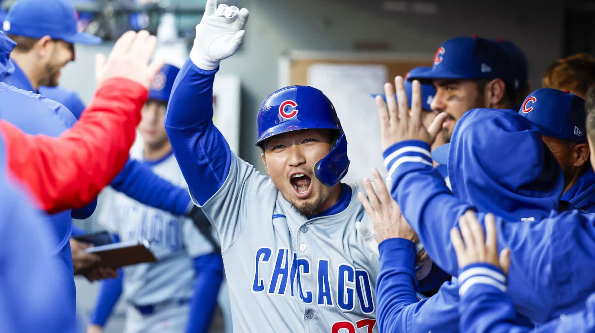Chicago Cubs right fielder Seiya Suzuki (27) high-fives teammates in the dugout after hitting a solo-home run against the Seattle Mariners during the third inning at T-Mobile Park