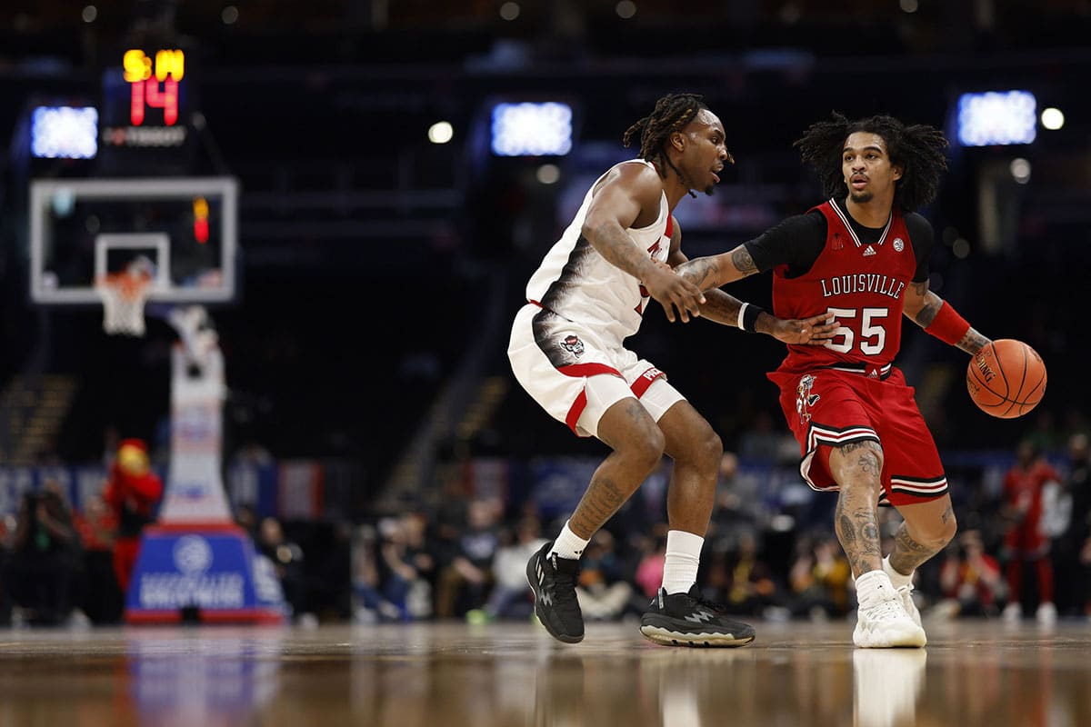 Louisville Cardinals guard Skyy Clark (55) drives to the basket as North Carolina State Wolfpack guard Jayden Taylor (1) defends in the first half at Capital One Arena.