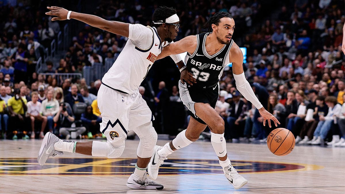 San Antonio Spurs guard Tre Jones (33) controls the ball against Denver Nuggets guard Reggie Jackson (7) in the first quarter at Ball Arena. 