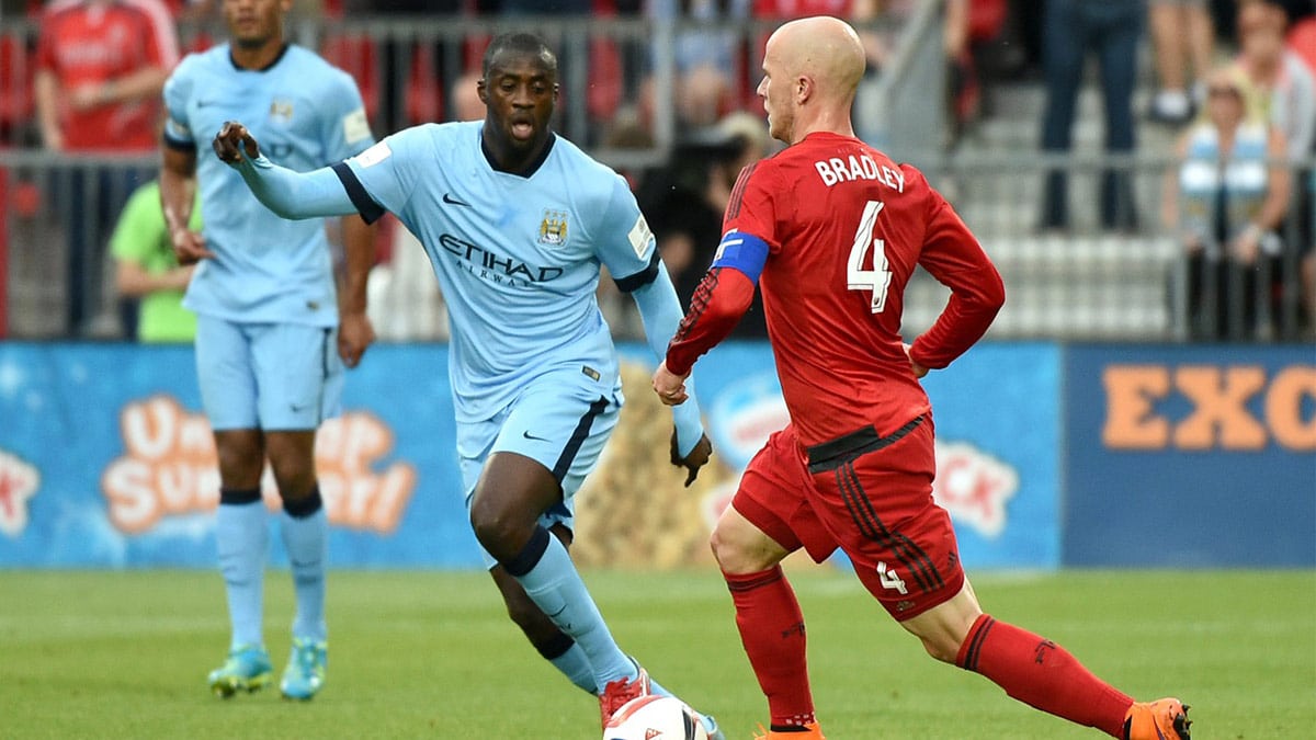 Toronto FC midfielder Michael Bradley (4) dribbles past Manchester City midfielder Yaya Toure (42) as defender Vincent Kompany (4) watches during the first half of an international club friendly at BMO Field. Manchester City won 1-0. 
