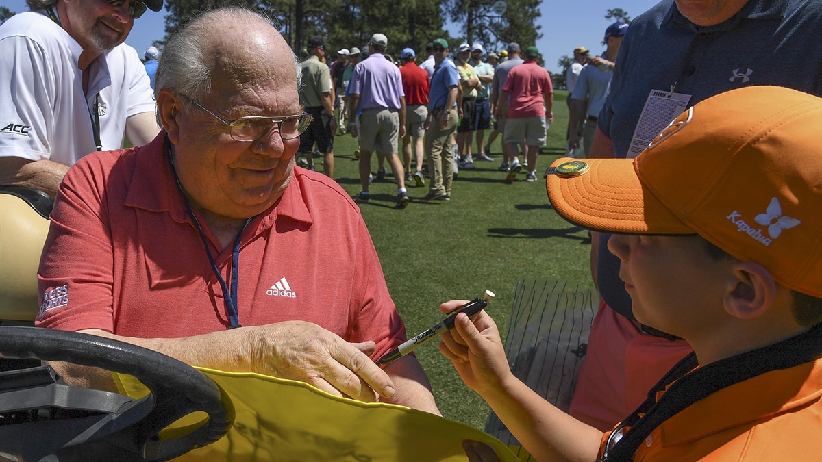CBS Broadcaster Verne Lundquist autographs a Masters flag for Jackson Heaton, 9 from Marietta, GA during Tuesday practice rounds at at Augusta National GC