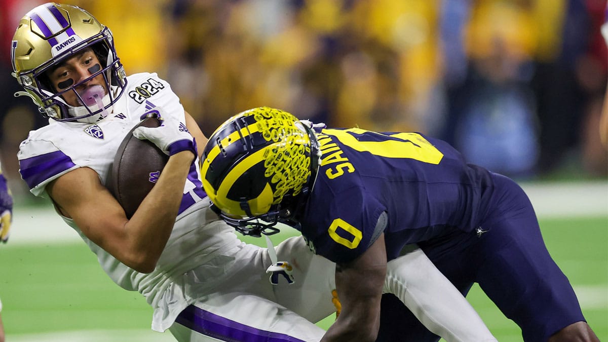 Washington Huskies wide receiver Jalen McMillan (11) is tackled by Michigan Wolverines defensive back Mike Sainristil (0) in the 2024 College Football Playoff national championship game at NRG Stadium