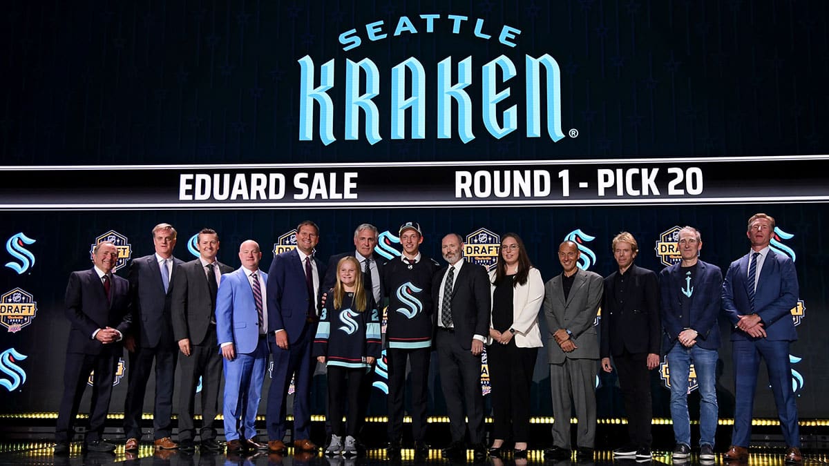 Seattle Kraken draft pick Eduard Sale stands with Kraken staff after being selected with the twentieth pick in round one of the 2023 NHL Draft at Bridgestone Arena.