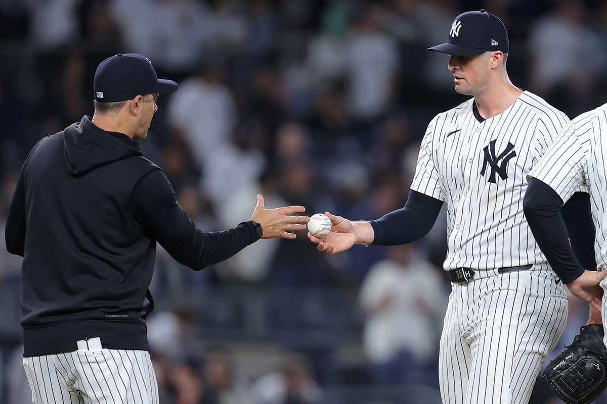 New York Yankees relief pitcher Clay Holmes (35) hands the ball to manager Aaron Boone (17) after being taken out of the game against the Seattle Mariners during the ninth inning at Yankee Stadium. 