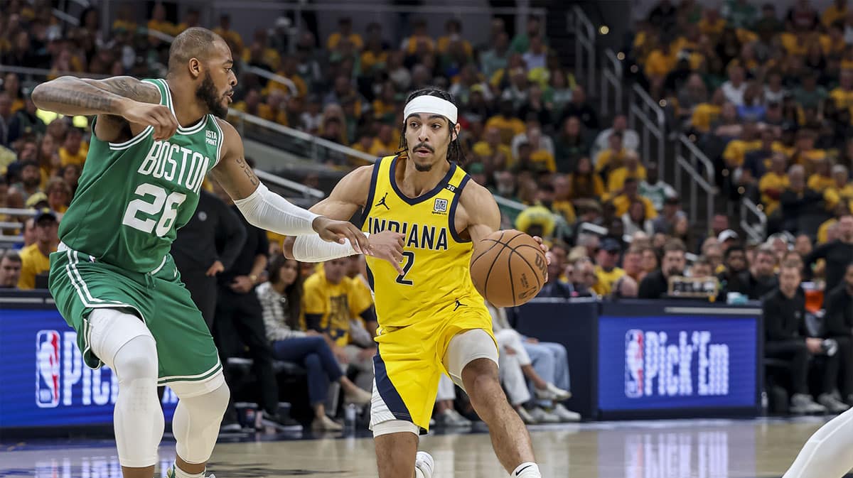 Indiana Pacers guard Andrew Nembhard (2) dribbles the ball while Boston Celtics forward Xavier Tillman (26) blocks during the second quarter during game four of the eastern conference finals for the 2024 NBA playoffs at Gainbridge Fieldhouse.