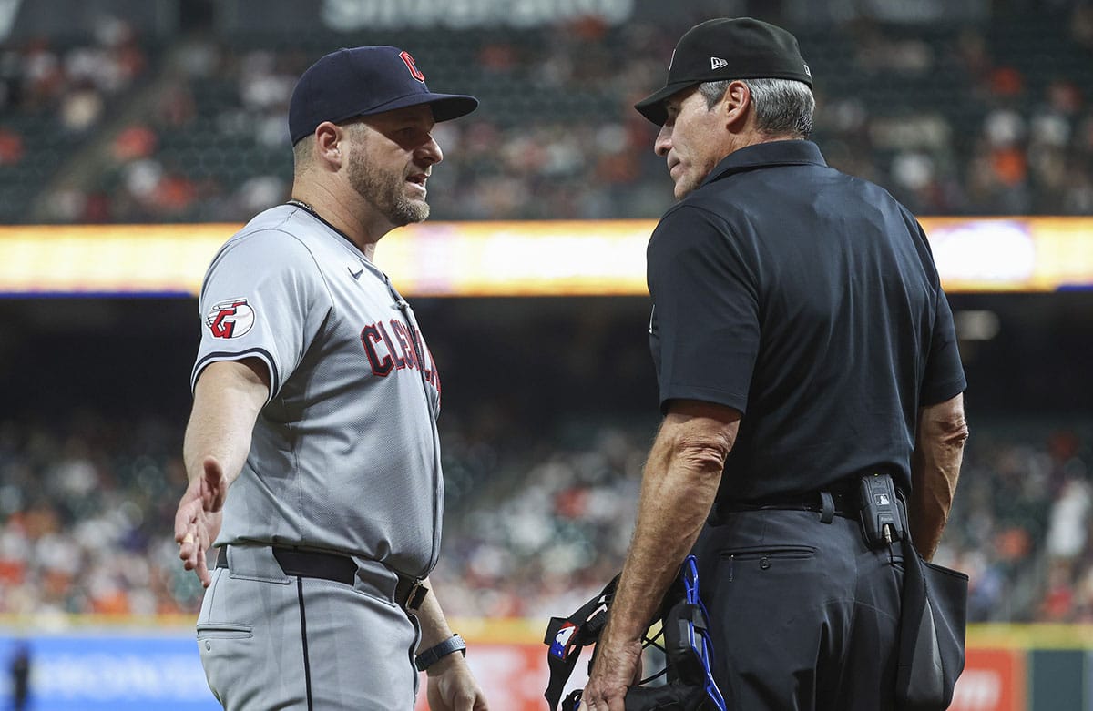 Cleveland Guardians manager Stephen Vogt (12) talks with home plate umpire Angel Hernandez during the third inning of the game against the Houston Astros at Minute Maid Park