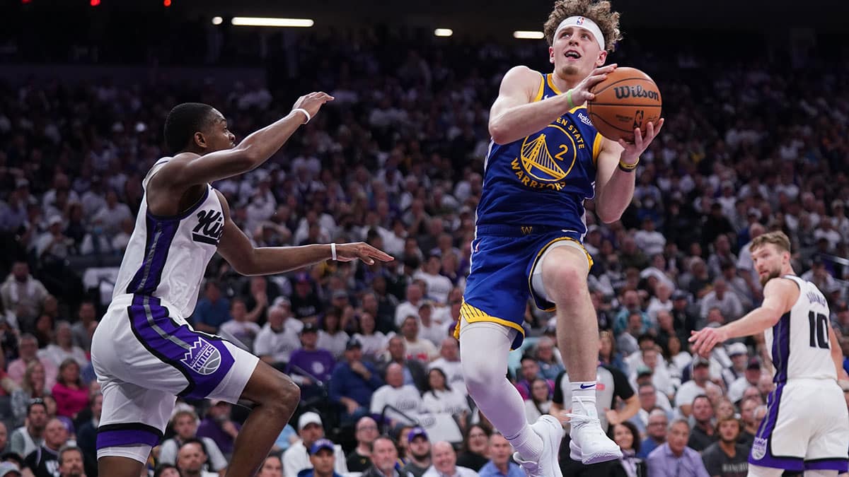 Golden State Warriors guard Brandin Podziemski (2) makes a layup next to Sacramento Kings guard De'Aaron Fox (5) in the second quarter during a play-in game of the 2024 NBA playoffs at the Golden 1 Center. 
