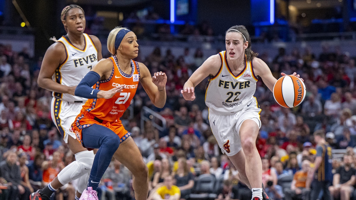 Indiana Fever guard Caitlin Clark (22) brings the ball up court while being defended by Connecticut Sun guard DiJonai Carrington (21) during the first half of an WNBA basketball game, Monday, May 20, 2024, at Gainbridge Fieldhouse