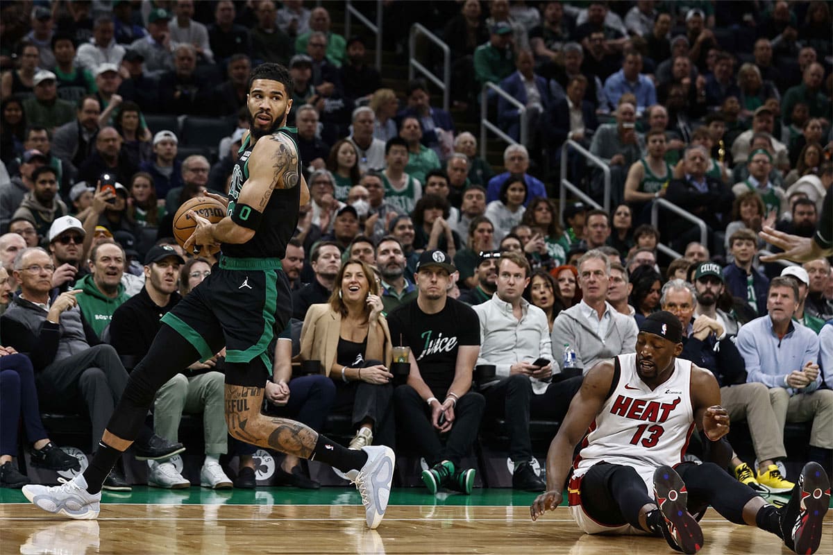 Boston Celtics forward Jayson Tatum (0) grabs a loose ball beside fallen Miami Heat center Bam Adebayo (13) during the first quarter of game five of the first round of the 2024 NBA playoffs at TD Garden.