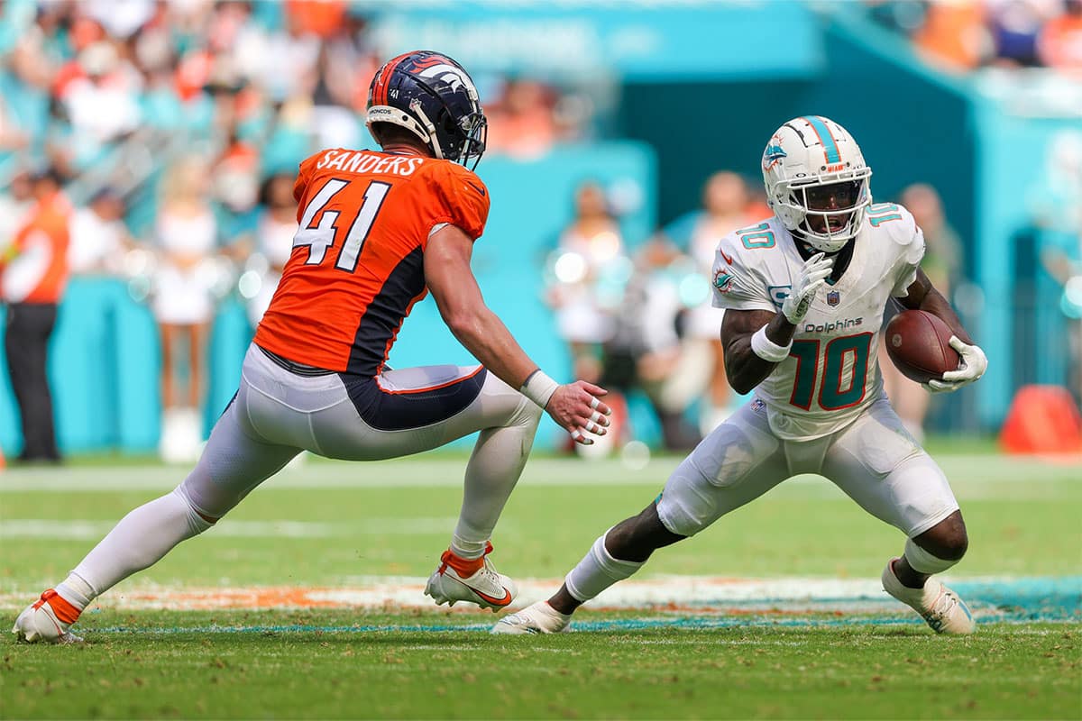 Miami Dolphins wide receiver Tyreek Hill (10) runs with the ball defended by Denver Broncos linebacker Drew Sanders (41) in the third quarter at Hard Rock Stadium.