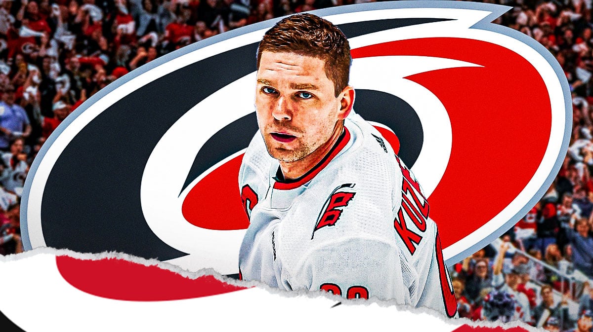 Evgeny Kuznetsov in middle of image looking happy, CAR Hurricanes logo, hockey rink in background