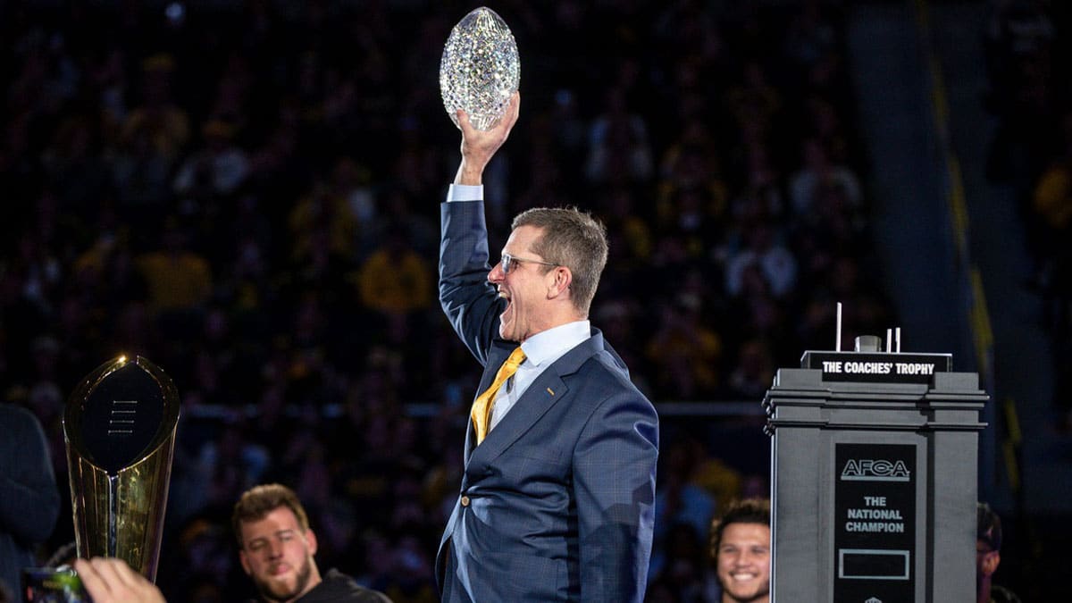 Jim Harbaugh holding up the crystal football trophy. 