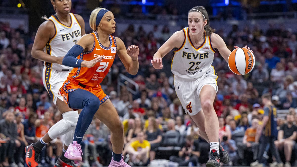 Indiana Fever guard Caitlin Clark (22) brings the ball up court while being defended by Connecticut Sun guard DiJonai Carrington (21) during the first half of an WNBA basketball game