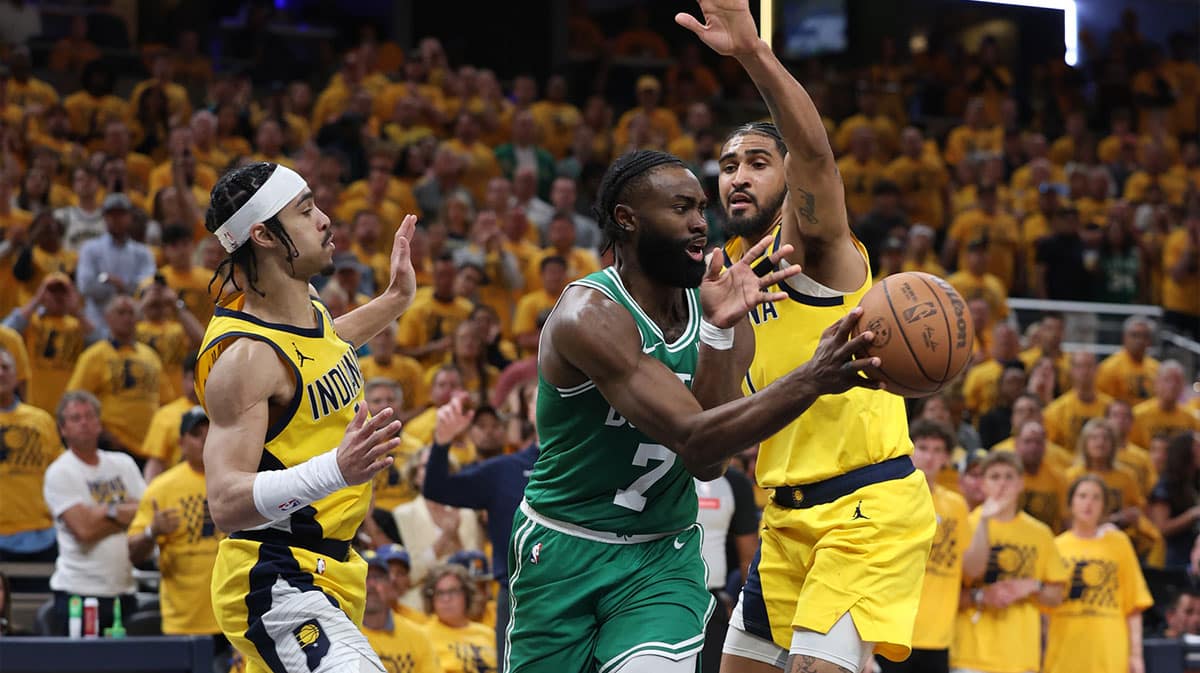 Boston Celtics guard Jaylen Brown (7) passes the ball against Indiana Pacers guard Andrew Nembhard (left) and forward Obi Toppin (right) during the fourth quarter of game three of the eastern conference finals in the 2024 NBA playoffs at Gainbridge Fieldhouse.