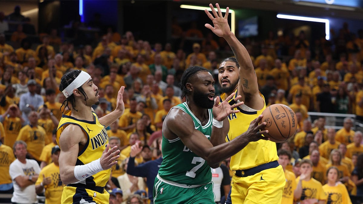 Boston Celtics guard Jaylen Brown (7) passes the ball against Indiana Pacers guard Andrew Nembhard (left) and forward Obi Toppin (right) during the fourth quarter of game three of the eastern conference finals in the 2024 NBA playoffs at Gainbridge Fieldhouse.