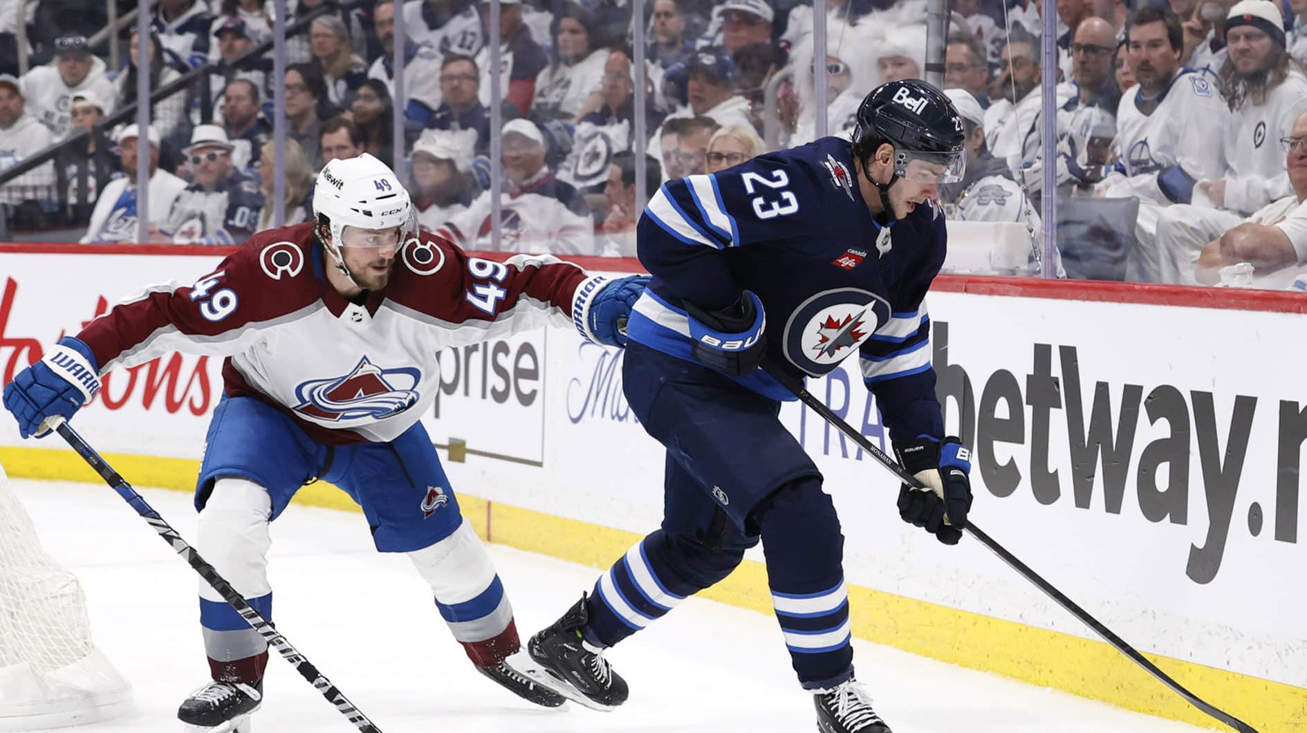 Winnipeg Jets center Sean Monahan (23) is checked by Colorado Avalanche defenseman Samuel Girard (49) in the second period in game five of the first round of the 2024 Stanley Cup Playoffs at Canada Life Centre.
