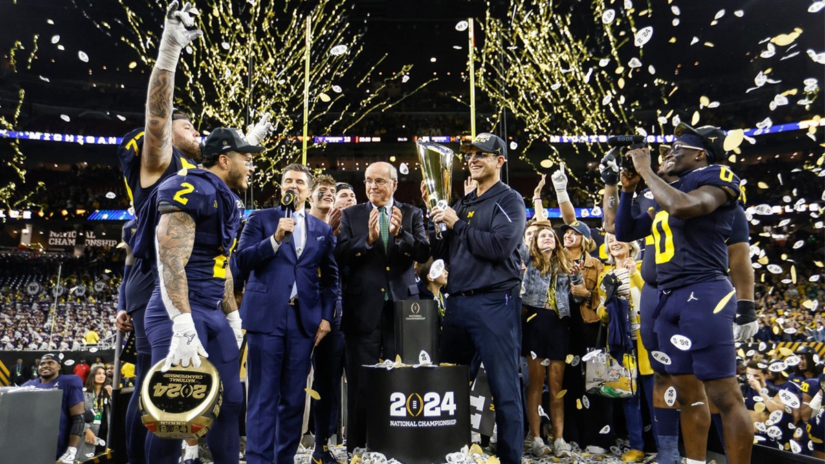 Michigan head coach Jim Harbaugh lifts the trophy to celebrate the 34-13 win over Washington to win the national championship game at NRG Stadium in Houston