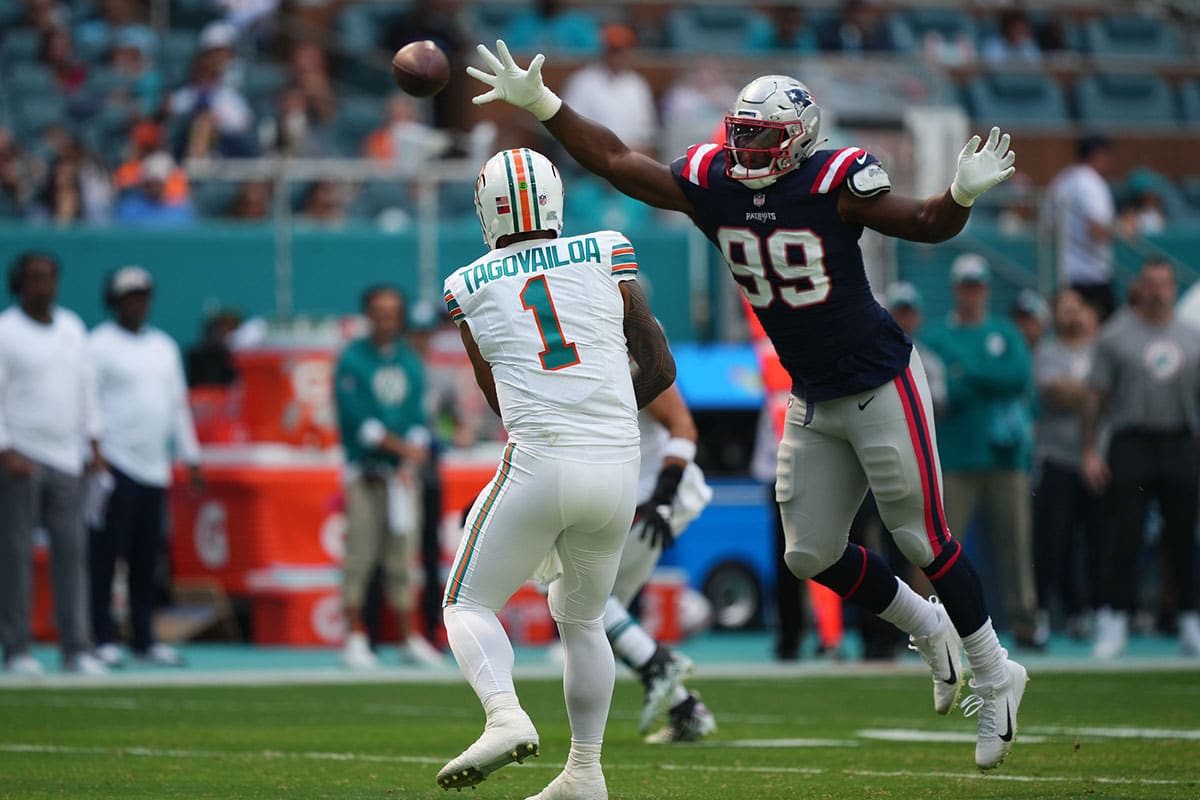 Oct 29, 2023; Miami Gardens, Florida, USA; New England Patriots defensive end Keion White (99) reaches for the pass of Miami Dolphins quarterback Tua Tagovailoa (1) during the first half at Hard Rock Stadium. 