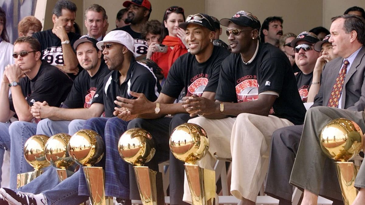 Chicago Bulls with their six championship trophies. Left to right in the front row are Luc Longley, Toni Kukoc, Ron Harper, Dennis Rodman (leaning back), Scottie Pippen, Michael Jordan and Chicago Mayor Richard Daley at a championship rally at Grant Park in Chicago