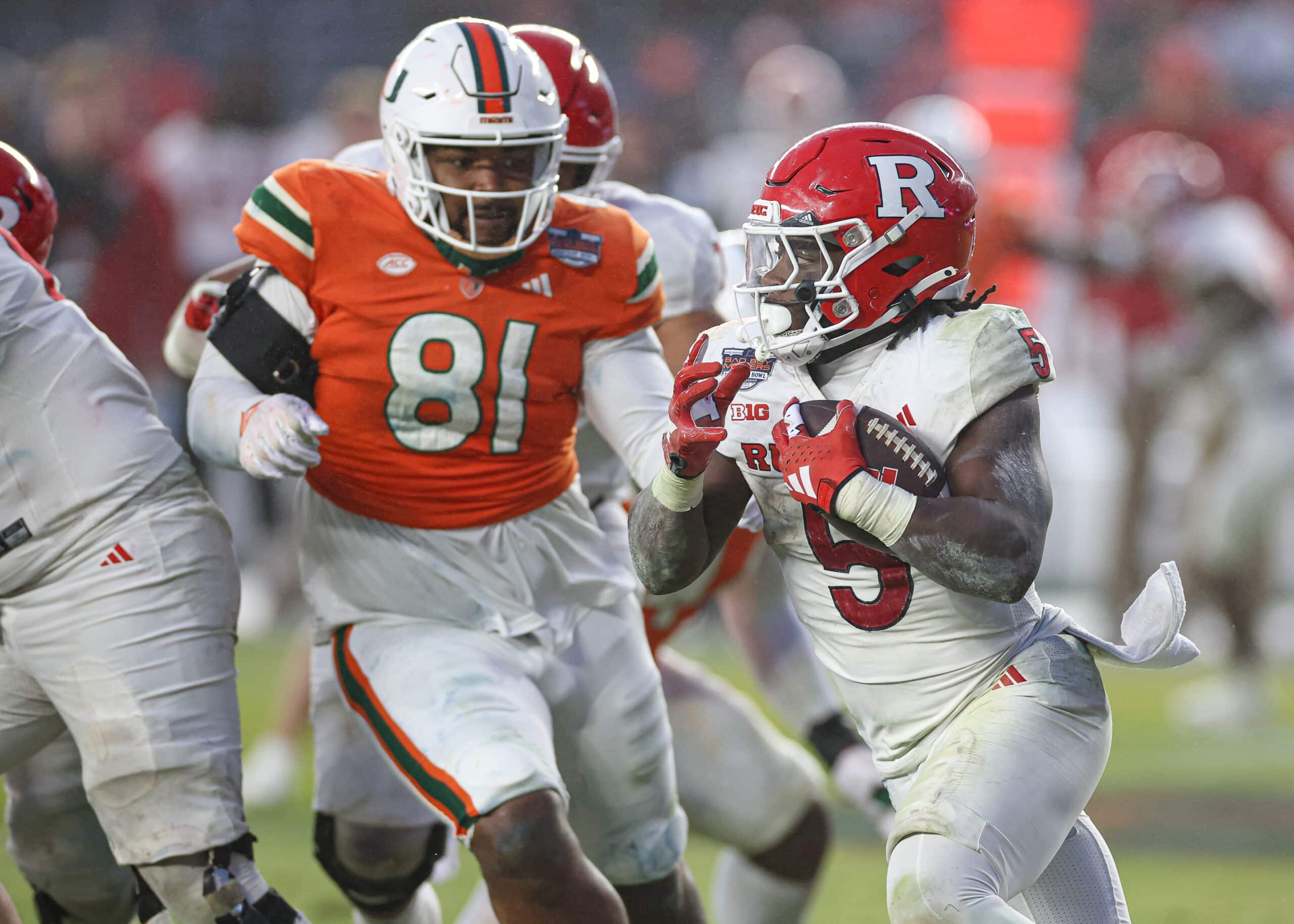 Dec 28, 2023; Bronx, NY, USA; Rutgers Scarlet Knights running back Kyle Monangai (5) carries the ball as Miami Hurricanes defensive lineman Jared Harrison-Hunte (81) pursues during the second half of the 2023 Pinstripe Bowl at Yankee Stadium. 