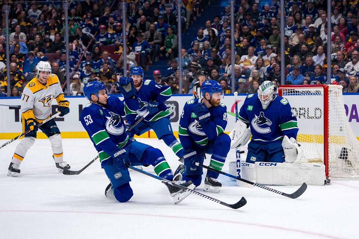 Vancouver Canucks forward Teddy Blueger (53) and defenseman Ian Cole (82) try to block a shot as goalie Thatcher Demko (35) watches against the Nashville Predators