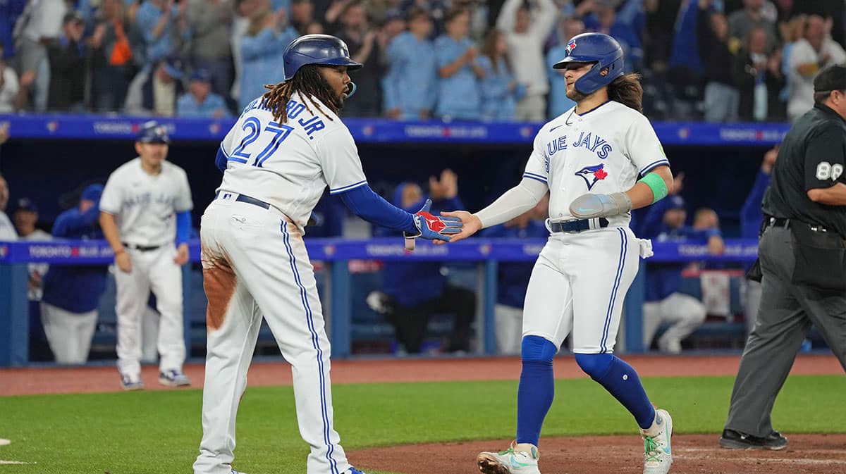 Toronto Blue Jays first baseman Vladimir Guerrero Jr. (27) and shortstop Bo Bichette (11) both celebrate scoring runs against the Tampa Bay Rays during the third inning at Rogers Centre.