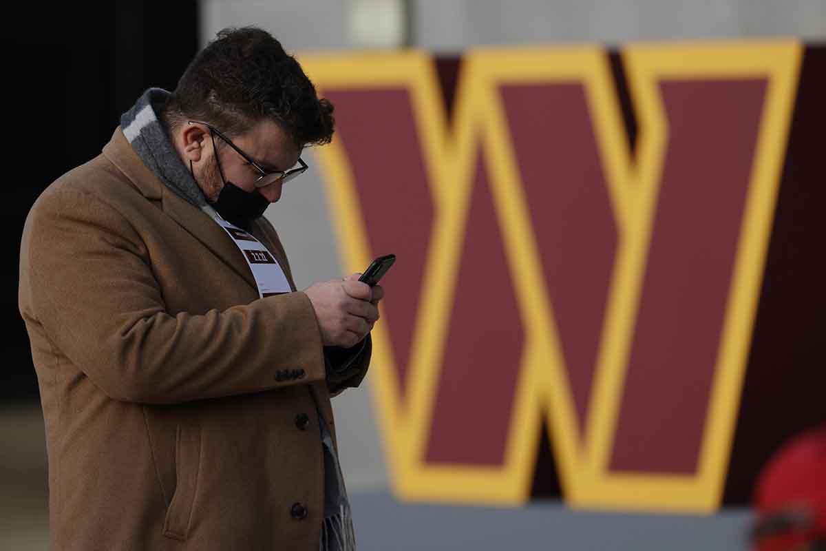 A member of the press tweets in front of a new team logo after the announcement during a press conference revealing the Washington Commanders as the new name for the formerly named Washington Football Team at FedEx Field. 