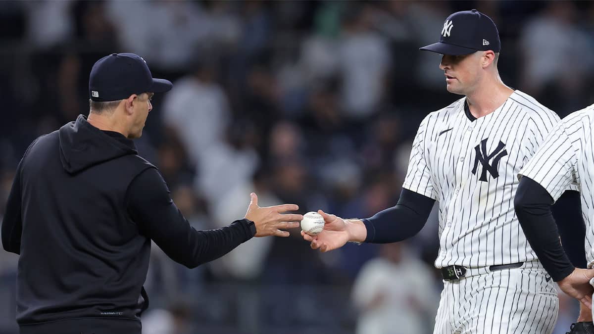 New York Yankees relief pitcher Clay Holmes (35) hands the ball to manager Aaron Boone (17) after being taken out of the game against the Seattle Mariners during the ninth inning at Yankee Stadium.