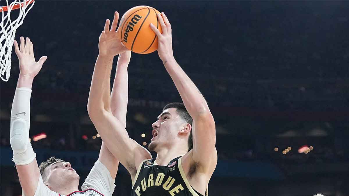 Connecticut Huskies center Donovan Clingan (32) and Connecticut Huskies guard Cam Spencer (12) defend the shot of Purdue Boilermakers center Zach Edey (15) during the NCAA Men’s Basketball Tournament Championship, Monday, April 8, 2024, at State Farm Stadium in Glendale, Ariz.