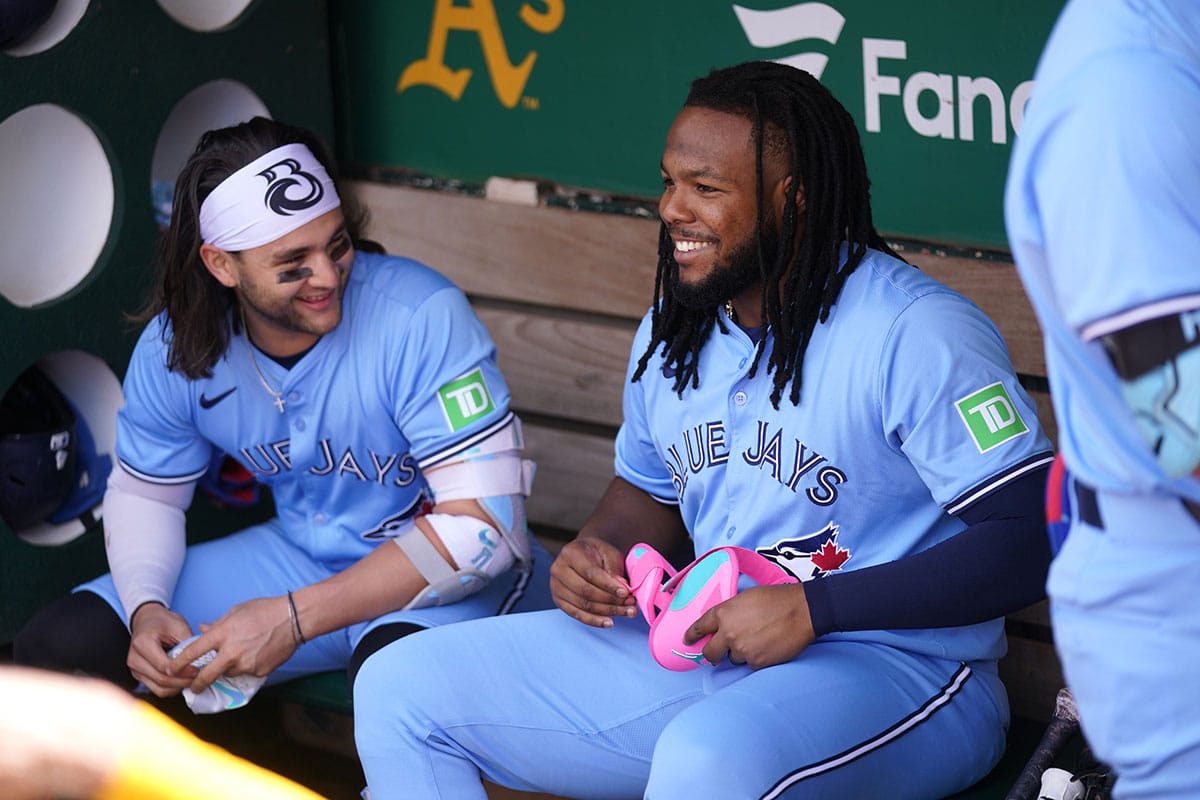 Toronto Blue Jays first baseman Vladimir Guerrero Jr. (27) sits next to shortstop Bo Bichette (11) before the start of the game against the Oakland Athletics at Oakland-Alameda County Coliseum.