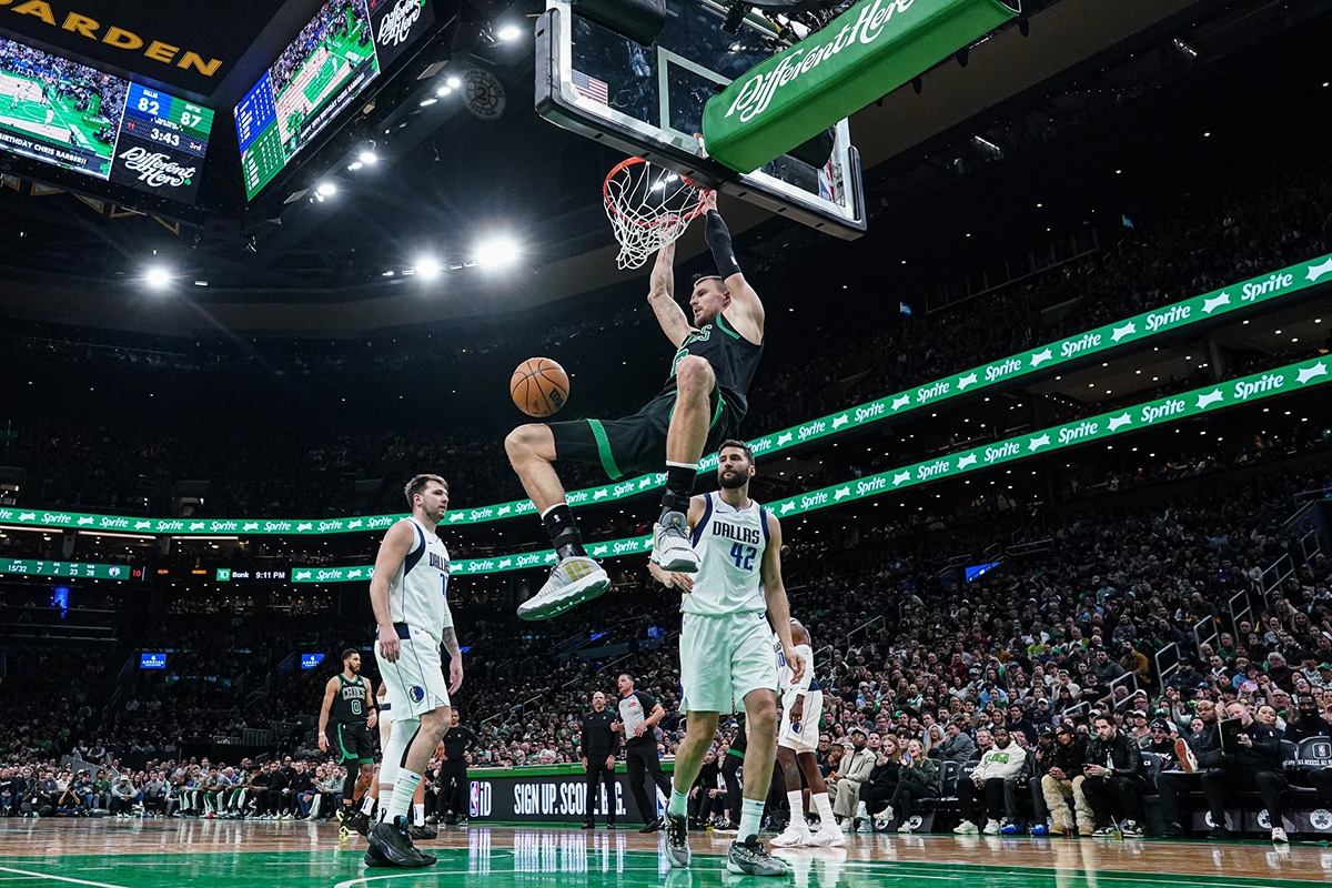 Mar 1, 2024; Boston, Massachusetts, USA; Boston Celtics center Kristaps Porzingis (8) makes the basket against Dallas Mavericks forward Maxi Kleber (42) and guard Luka Doncic (77) in the second half at TD Garden. Mandatory Credit: David Butler II-USA TODAY Sports