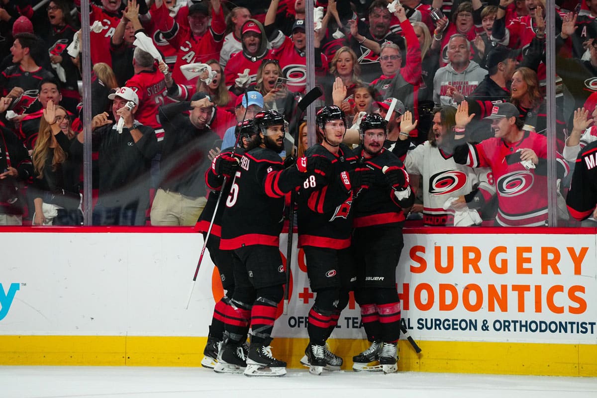 Carolina Hurricanes center Martin Necas (88) celebrates his goal with defenseman Dmitry Orlov (7) and defenseman Jalen Chatfield (5) against the New York Rangers during the first period in game six of the second round of the 2024 Stanley Cup Playoffs at PNC Arena.