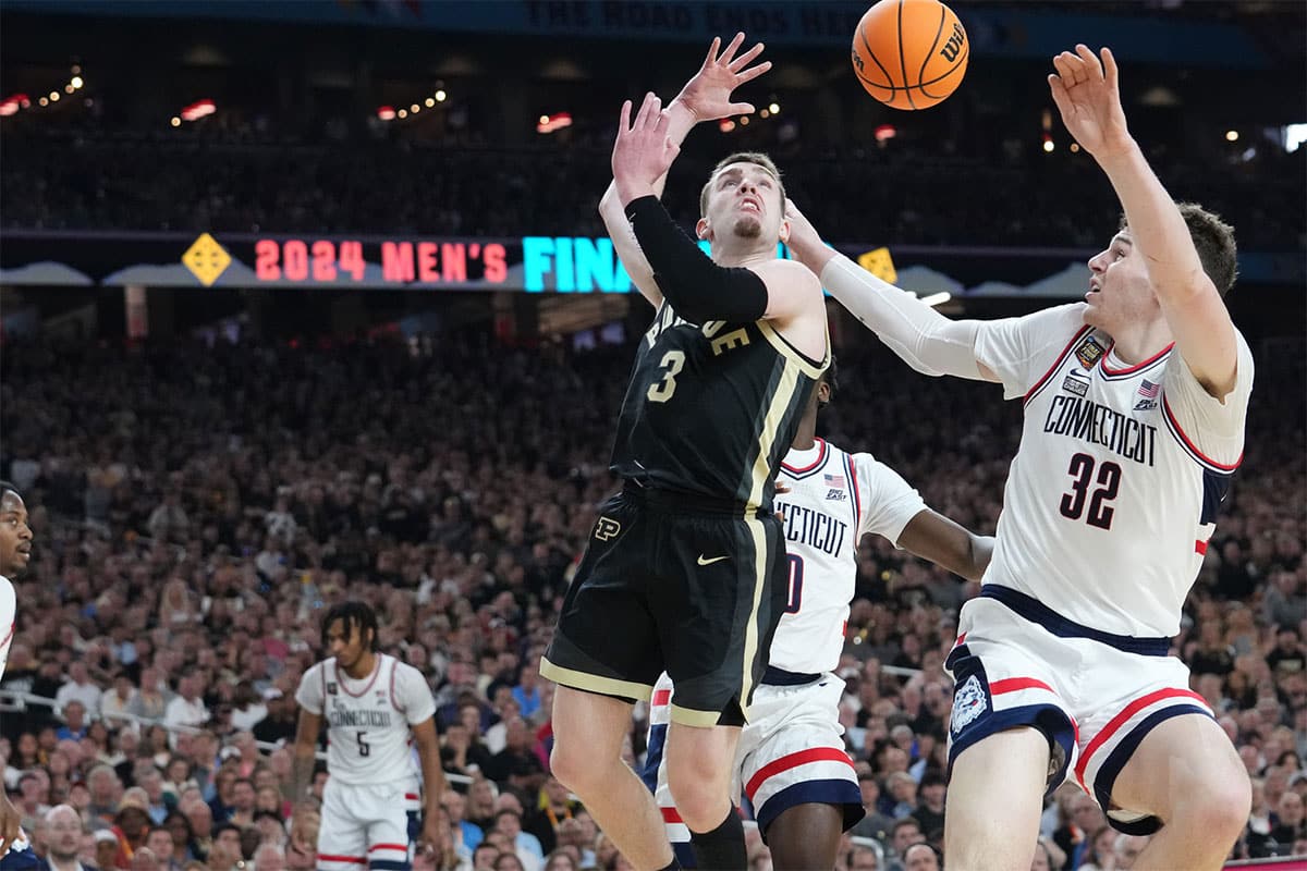 Purdue Boilermakers guard Braden Smith (3) passes the ball over Connecticut Huskies center Donovan Clingan (32) during the Men's NCAA national championship game at State Farm Stadium in Glendale on April 8, 2024.