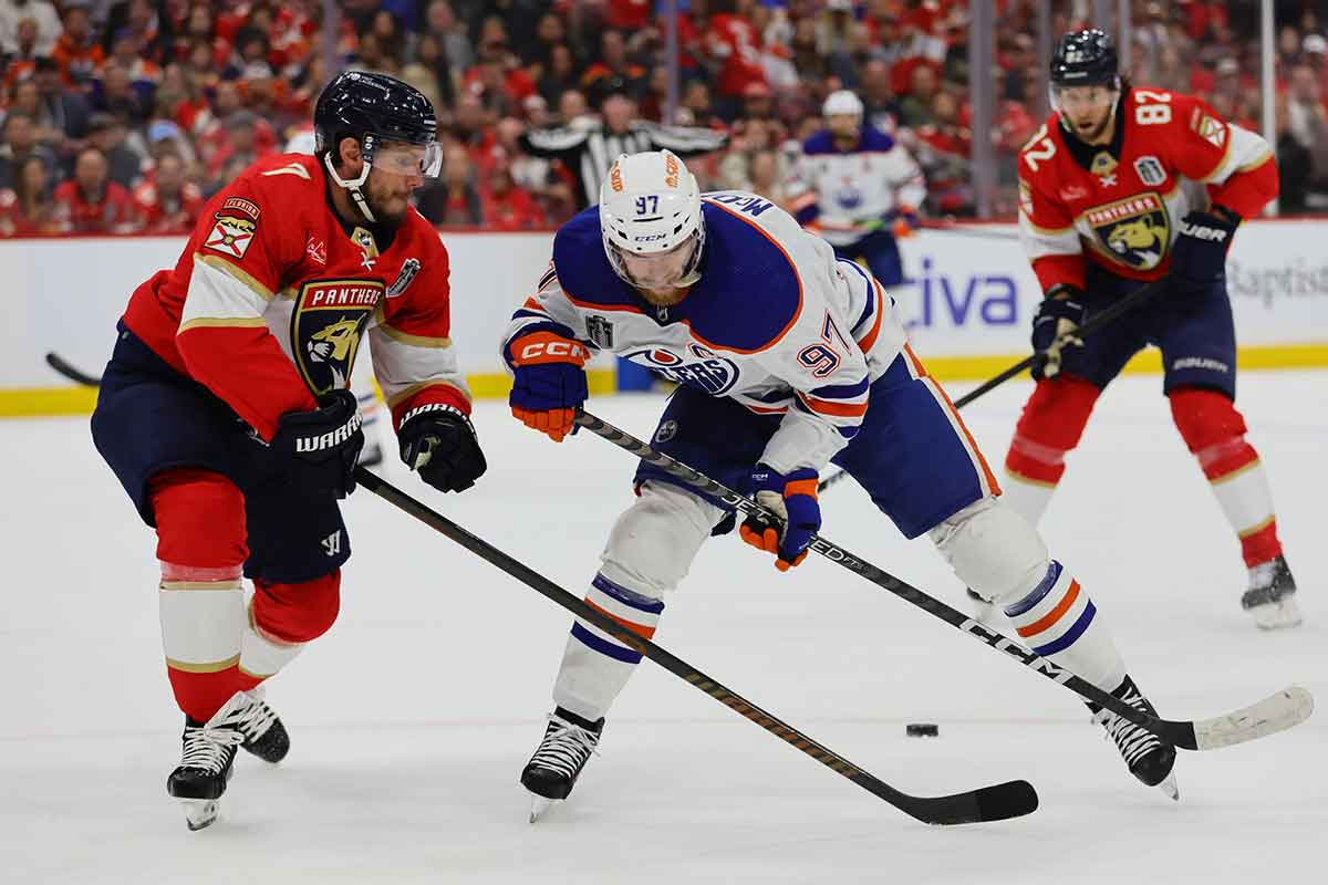 Edmonton Oilers forward Connor McDavid (97) battles for the puck against Florida Panthers defenseman Dmitry Kulikov (7) during the first period in game one of the 2024 Stanley Cup Final at Amerant Bank Arena.