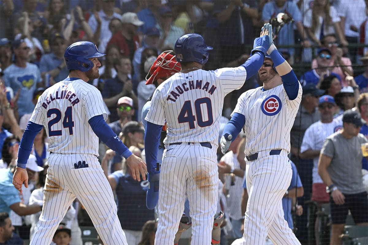 Chicago Cubs outfielder Ian Happ (8), right, high fives outfielder Cody Bellinger (24) and outfielder Mike Tauchman (40) after they score on Happ’s three run home run during the seventh inning at Wrigley Field.