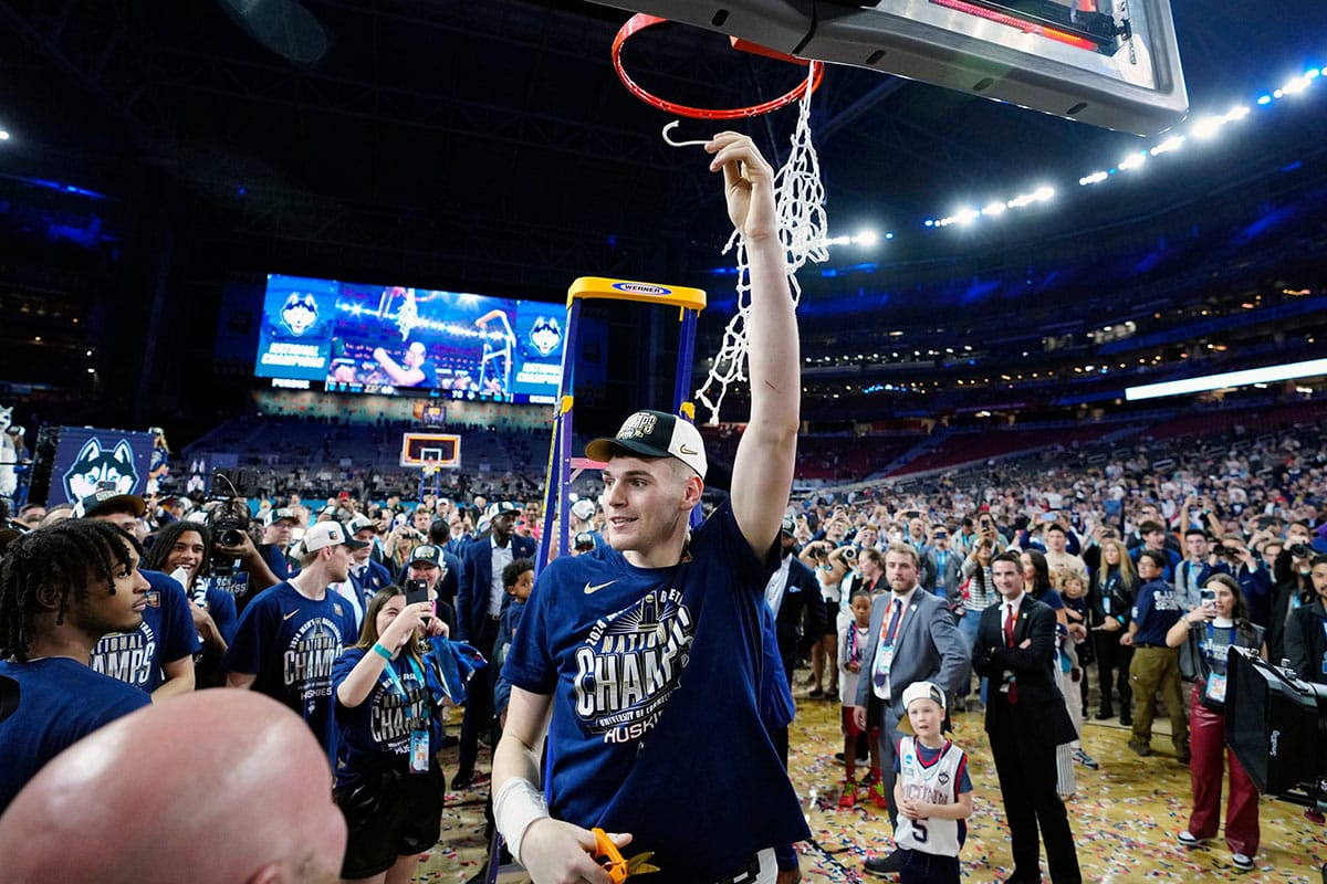 Connecticut Huskies center Donovan Clingan (32) cuts the cut after defeating the Purdue Boilermakers in the national championship game of the Final Four of the 2024 NCAA Tournament at State Farm Stadium in Glendale on April 8, 2024.