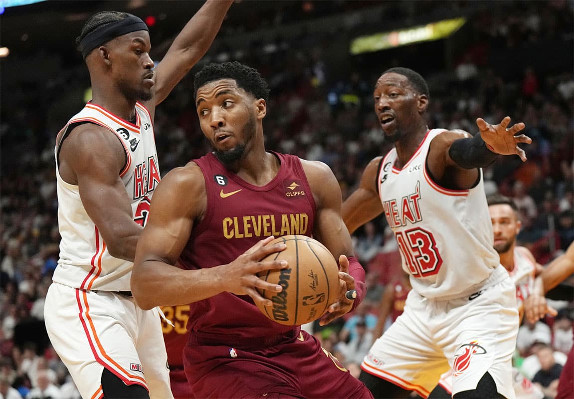 Cleveland Cavaliers guard Donovan Mitchell (45) looks to pass the ball as Miami Heat forward Jimmy Butler (22) and center Bam Adebayo (13) defend in the second half at Miami-Dade Arena.