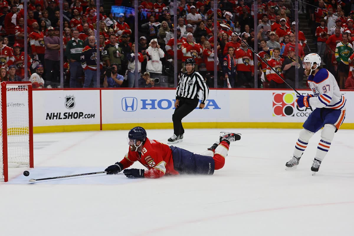 Florida Panthers forward Matthew Tkachuk (19) reaches for the puck on an empty net attempt on goal by Edmonton Oilers forward Connor McDavid (97) during the third period in game five of the 2024 Stanley Cup Final at Amerant Bank Arena.