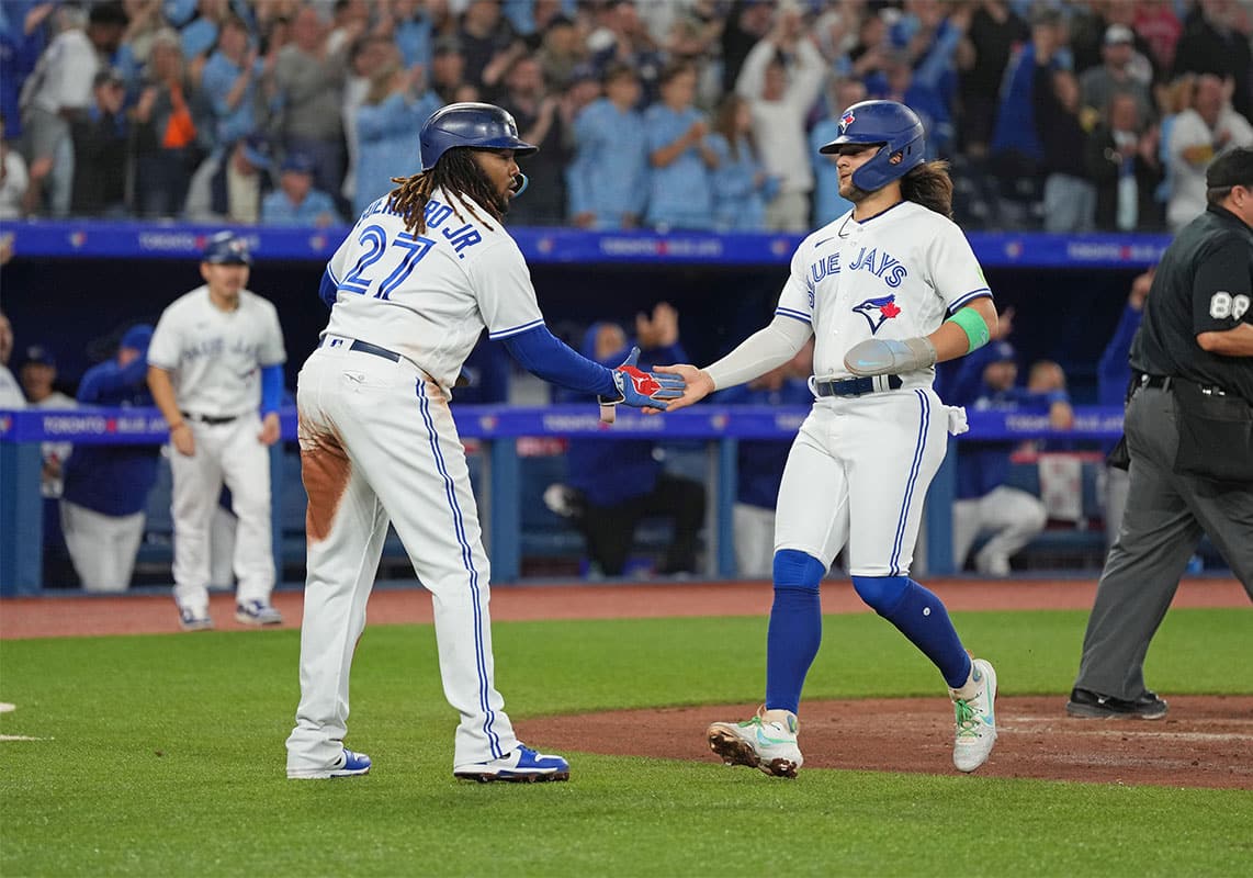Toronto Blue Jays first baseman Vladimir Guerrero Jr. (27) and shortstop Bo Bichette (11) both celebrate scoring runs against the Tampa Bay Rays during the third inning at Rogers Centre. 