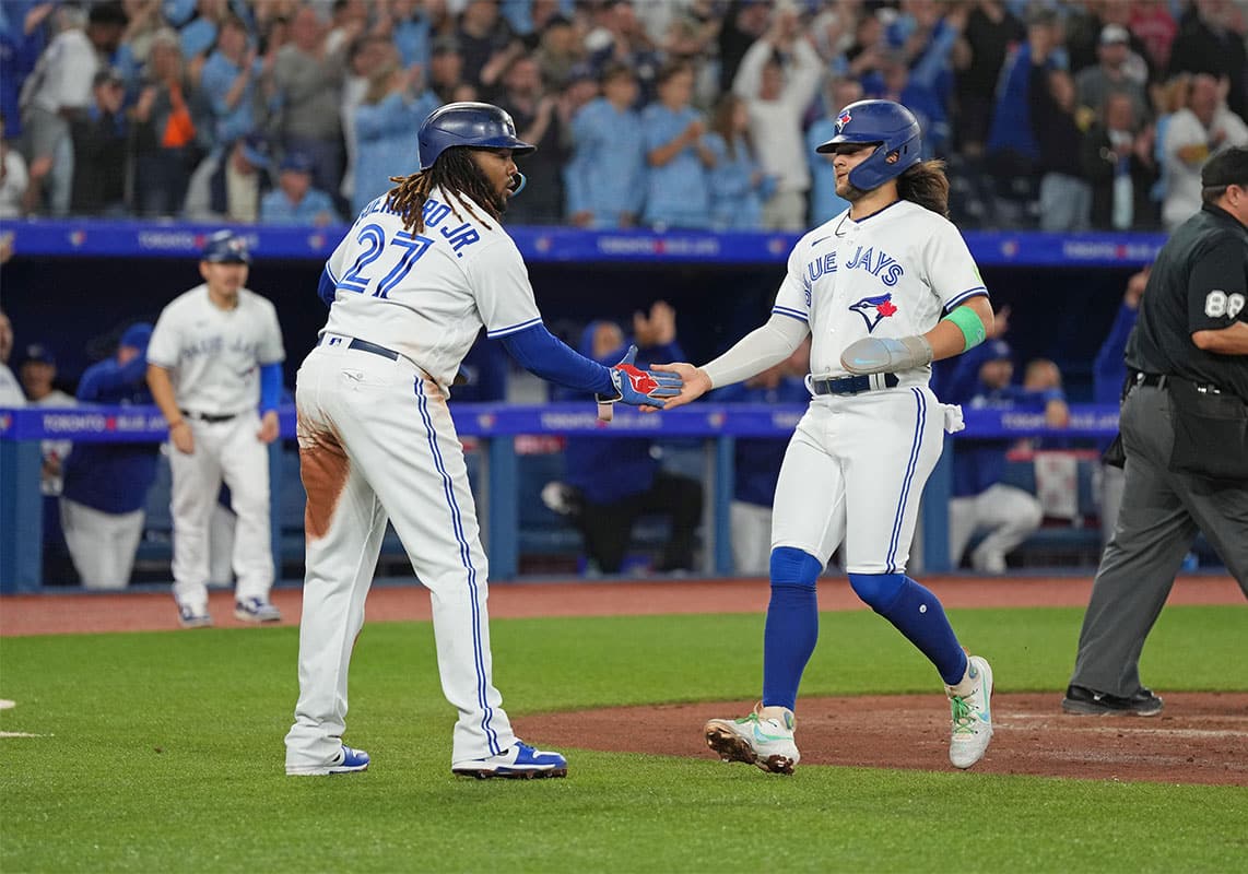 Toronto Blue Jays first baseman Vladimir Guerrero Jr. (27) and shortstop Bo Bichette (11) both celebrate scoring runs against the Tampa Bay Rays during the third inning at Rogers Centre.