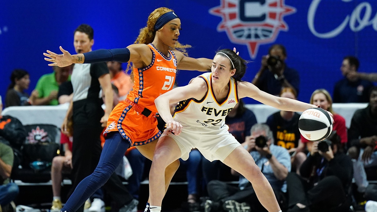 Jun 10, 2024; Uncasville, Connecticut, USA; Indiana Fever guard Caitlin Clark (22) moves the ball against Connecticut Sun guard DiJonai Carrington (21) in the first quarter at Mohegan Sun Arena. Mandatory Credit: David Butler II-USA TODAY Sports, Teresa Weatherspoon, Sky fans watch from TV 